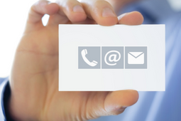 Uma pessoa segurando um papel com símbolos de telefone, email e envelope