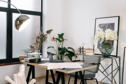 Ambiente com uma mesa, cadeiras, quadro, decorações e uma janela